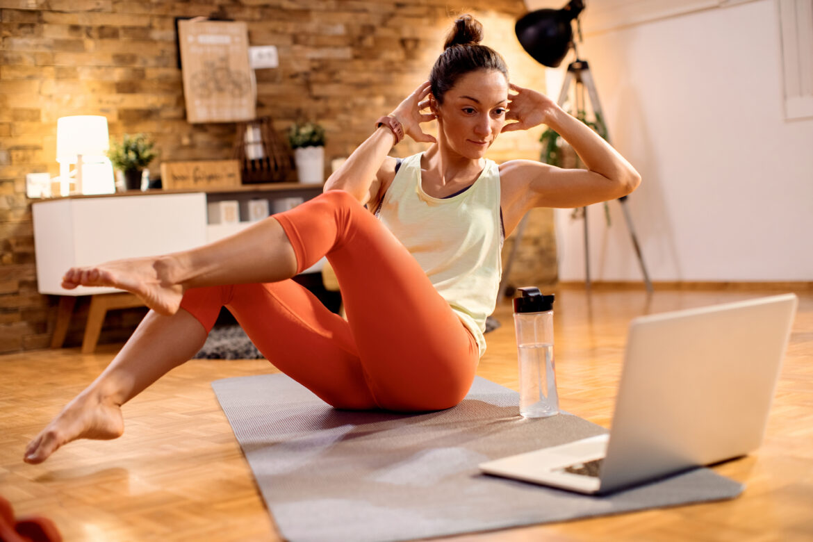 Sportswoman doing abs exercises while following online tutorial